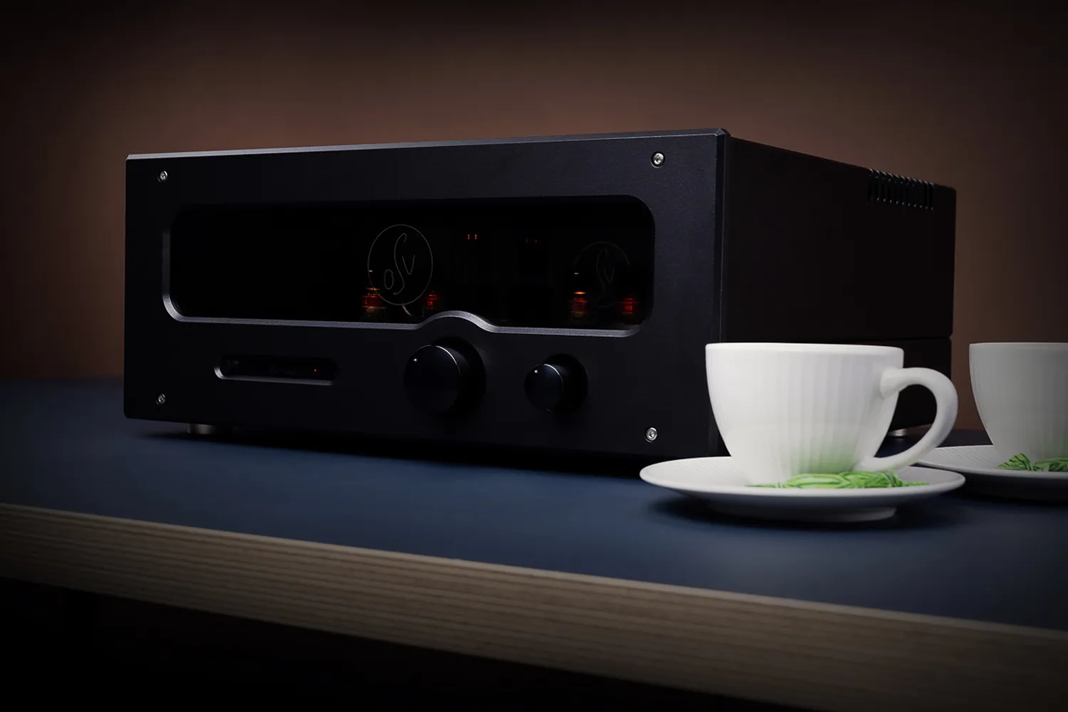 An OSV Audio amplifier at home on a low table, both tubes glowing behind its window